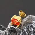 Detalle macro de pendiente de oro con circón naranja sobre piedra mineral negra - Oro Circonita Naranja