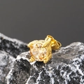 Primer plano de pendiente de acero dorado con circón redondo sobre piedra oscura - Dorado Piedra Champaña