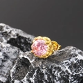 Macro shot of a pink zircon earring with gold prong setting on a black volcanic stone - Gold Pink Zirconia