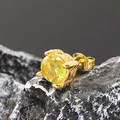 Primer plano macro de pendiente de acero inoxidable dorado con circón amarillo sobre piedra - Oro Circonita Amarilla