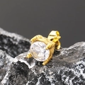 Primer plano de pendiente de oro con un gran circón sobre una piedra mineral de color oscuro - Dorado Circonita Blanca
