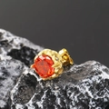 Macro detail of vintage stud earring featuring a dark red gemstone in a gold petal setting - Gold Orange Zirconia