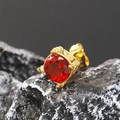 Vista macro del pendiente chapado en oro con circón rojo sobre fondo de piedra oscura - Oro Circonita Roja
