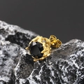 Macro shot of gold-plated titanium steel stud earring with black stone on volcanic rock - Gold Black Zirconia