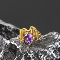 Macro shot of punk gothic wing earring with a purple zircon stone on a dark rock - Single Piece / Gold Purple Zirconia