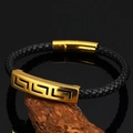 Macro shot of black braided leather bracelet featuring golden geometric engraved metal bar - Black
