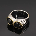 Gros plan d'une bague en titane argenté avec deux zircons noirs en forme de cœur et bord doré - Or Pierre Noire