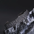 Detail eines Wikinger-Armreifs mit nordischen Runen und Triquetra-Knoten auf schwarzem Fels - Antik-Silber