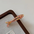 Gros plan détaillé d'une pince à cheveux en acétate en forme de poisson avec strass - Orange