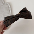 Detailed macro view of dark leopard bow hair clip with a gold LOVE engraved buckle - Dark Tortoiseshell Leather Hair Clip