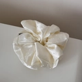 Close-up of a cream satin scrunchie with subtle polka dots and smooth silk texture - White