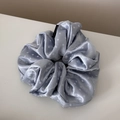 Macro detail of light blue satin scrunchie with white polka dots and fashion label - Blue