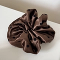 Détail d'un chouchou en satin à pois avec une texture plissée douce en marron foncé - Marron