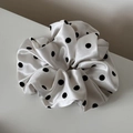Détail d'un grand chouchou en satin blanc avec motif à pois noirs classique et chic - Blanc Cassé