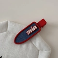 Dettaglio molletta per capelli rossa con inserto denim blu e scritte bianche 'min' - Forma Senza Tracce
