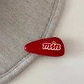 Macro-opname van een rode druppelvormige haarclip met wit min-letterontwerp op stof - Hoogverzadigd Rood-Brede Driehoek