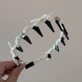 Detalle de diadema gótica con lazos blancos, pedrería y pinchos negros en la mano - Aro de Dientes Largos Ondulados / Lazo de Strass Blanco