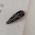 Primo piano del fermaglio per capelli leopardato su uno sfondo di lino testurizzato - Leopardo Marrone Goccia d'Acqua