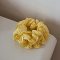 Detail of a ruffled bright yellow scrunchie made from pleated fabric for ponytail styling - Yellow