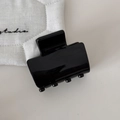 Close-up of black glossy resin rectangle hair claw clip on soft textured background - Black