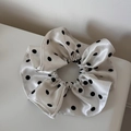 Gros plan sur le chouchou élégant à pois en satin avec texture lisse et design plissé - Blanc