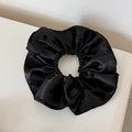 Vue macro détaillée du chouchou noir à pois avec une texture en satin de soie lisse - Noir