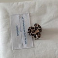 Close-up of a mini leopard print hair claw clip on soft beige fabric background - Mini Type / Leopard Print