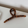 Macro di una grande pinza per capelli tartarugata con finitura lucida su fondo bianco - Leopardo Caffè Forma Appendiabiti