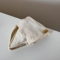 Detalle de tela de satén crema con etiqueta dorada de la marca en el accesorio para el pelo - Pinza para el Pelo Blanco Crema Etiqueta Dorada