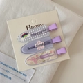 Dettaglio di tre fermagli per capelli viola con motivi floreali e arcobaleno su carta - Molletta Arcobaleno Viola