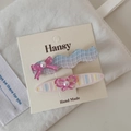Détail de 2 barrettes à fleurs avec carreaux bleu-violet et nœud rose sur carte - Pince Ovale Vague Bleu Rose