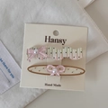 Détail de barrettes roses à fleurs avec nœuds et perles sur carte de présentation - Pince Ovale Vague Pois Jaune