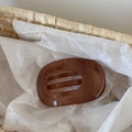 Macro detail of amber brown resin hair claw clip in a woven basket with minimalist design - Brown