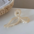 Dettaglio di un fermaglio per capelli a fiocco color crema con elegante trama marmorizzata - Beige