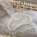 Dettaglio di un grande fermaglio per capelli crema con design a onde su sfondo intrecciato - Bianco