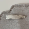 Detailansicht der beigen Denim-Haarklammer in Tropfenform mit feiner Nähtextur auf Stoff - Naturweiß Stoff Tränenclip