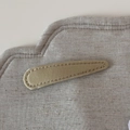 Nahaufnahme der goldenen Satin-Haarklammer in Tropfenform mit feiner Naht auf grauem Stoff - Khaki Stoff Tränenclip