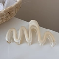 Dettaglio di una molletta per capelli ondulata in resina crema lucida e traslucida - Albicocca