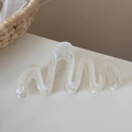 Dettaglio macro di un mollettone per capelli in resina con trama bianca ondulata - Bianco