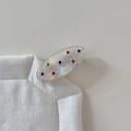Dettaglio di un fermaglio ovale in acetato con finitura perlata e strass colorati - Bianco Trasparente