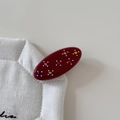Macro di una molletta ovale rossa in acetato con strass colorati e piccole perline fini - Rosso