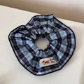 Dettaglio di scrunchie a quadri blu con patch Sweat Dog e accento con bottone blu - Scrunchie / Quadri Blu