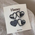 Detail view of two heart-shaped hair clips with polka dots and stripes on a display card - Stripe And Polka Dot Clips / Gray