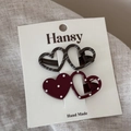 Detail of polka dot and striped heart-shaped hair clips on a cardboard display - Polka Dot And Diagonal Stripe Clips / Reddish Brown