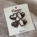 Close-up of heart-shaped hair clips with white polka dots and stripes on display card - Dark Brown