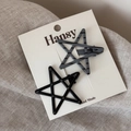 Close-up of star-shaped duckbill hair clips in black and grey patterns on a display card - Black and Gray