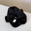 Close-up of black fabric scrunchie featuring a white Hand Made label on neutral background - Scrunchie / Black