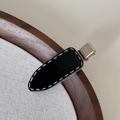 Dettaglio di un fermaglio per capelli nero minimalista con cuciture bianche e fibbia in metallo - Stile Ellisse Tratteggiato (FJ892858) / Clip Nera Tratteggiata
