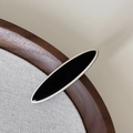 Dettaglio di un fermaglio per capelli ovale nero e crema su un vassoio di legno - Stile Patchwork Ellisse (FJ892858) / Clip Nera Ellisse Lunga
