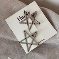 Detailed view of two star-shaped hair clips with polka dots and stripes on a display card - Beige